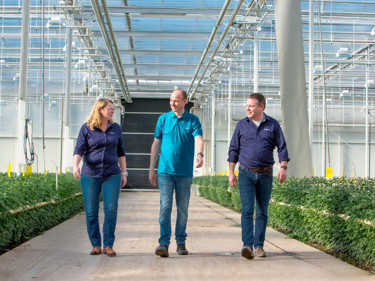 three people walking through a greenhouse